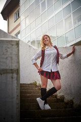 Young girl with short hair in a school checkered uniform outdoors.
