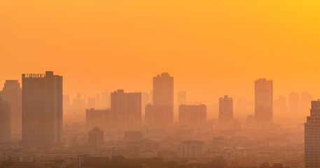 Air pollution. Smog and fine dust of pm2.5 covered city in the morning with orange sunrise sky....