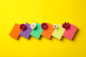 Color sponges for cleaning and flowers on yellow background