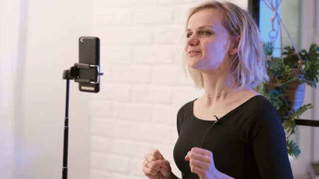 Young woman blogger influencer talking with followers, live streaming, looking to smartphone screen at home. Making call friends and parents.