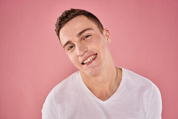 Fototapeta premium cheerful man in white t-shirt smile emotions close-up pink background studio