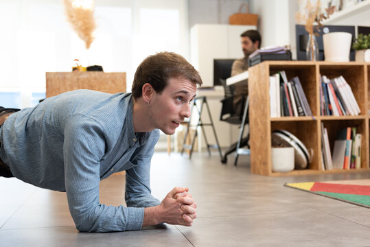 Handsome man having a break to work out in the office. Healthy lifestyle at work concept.