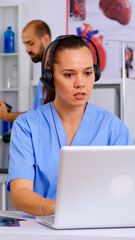 Medical assistant operator with headphone consulting patients during telehealth discussion in hospital. Healthcare physician in medicine uniform, doctor nurse helping with appointment