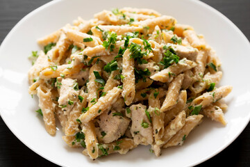 Homemade Chicken Alfredo Penne with Parsley on a black background, side view. Close-up.