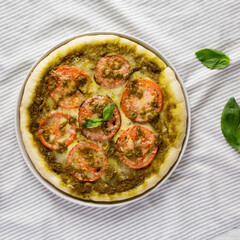 Homemade Pesto Pizza with Fresh Tomatoes and Mozzarella on cloth, overhead view. Flat lay, top view, from above.