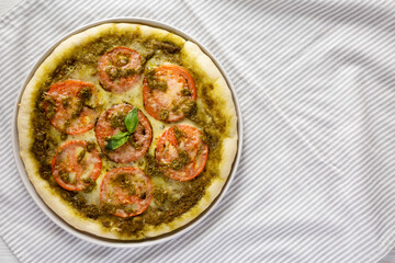 Homemade Pesto Pizza with Fresh Tomatoes and Mozzarella on cloth, overhead view. Flat lay, top view, from above. Space for text.