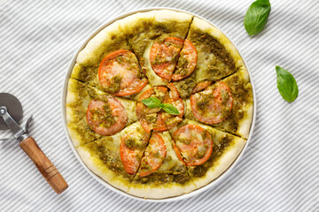 Homemade Pesto Pizza with Fresh Tomatoes and Mozzarella on cloth, top view. Flat lay, overhead, from above.