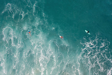 Aerial photograph of the ocean with crashed waves and surfers