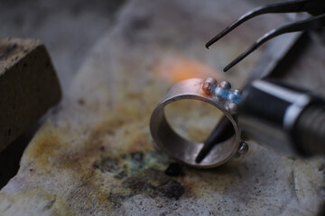 Obraz na płótnie Canvas Macro shot. Craft jewelery making with professional tools. A handmade jeweler process, manufacture of jewellery. Melting metal