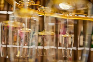 Selective focus of clean empty wine glasses hanging in bar counter
