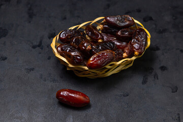 Dates on a black background. Dried fruits. Dried dates are in a small basket