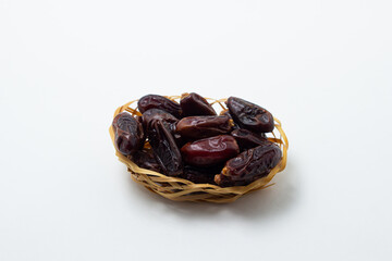 Dates on a white background. Dried fruits. Dried dates are in a small basket