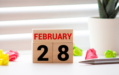 Cube shape calendar for February 28 on wooden surface with empty space for text.