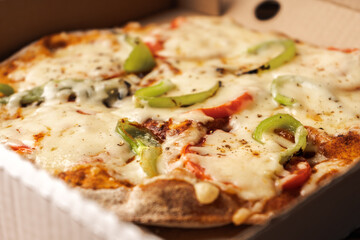 Vegetarian pizza with paprika on wholegrain dough in a cardboard box close-up