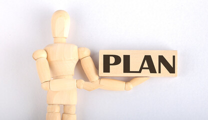 Wooden man shows with a hand to block with text PLAN