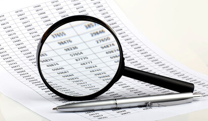 Graphs, magnifier and pen. Analyzing finances. Concept