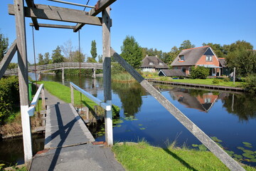 Dwarsgracht, a picturesque village in the countryside near Giethoorn, with water canals, wooden footbridges and houses with thatched roof, Overijssel, Netherlands
