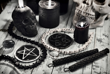 Evil still life with black candles and scary symbols of devil with pentagram.