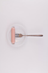 raw sausage with fork on white plate on white background
