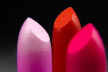 Pink, deep red, and fuchsia, magenta colored perfect, new lipstick with black background....