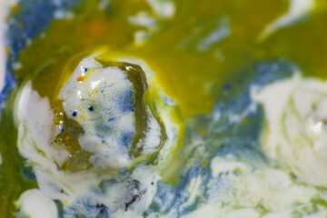 Luqiud vivid blue and ochre color mixing together on white background. Painting, splash marble...
