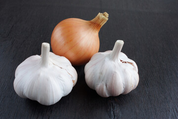 unpeeled ripe onion and garlic on a dark wooden background