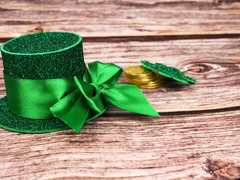 Green hat with golden coins and shamrock on wooden table, st patricks day concept