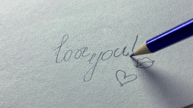 Hand writing with a pencil inscription on white paper - I love you