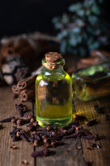 Clove oil in a bottle of glass on the table. Bottle of clove essential oil with dried cloves on the wooden background.