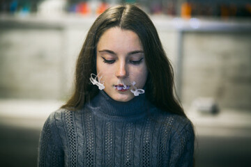 Vaping teenager. Young pretty white caucasian teenage girl with long hair smoking an electronic...