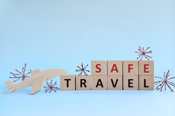 Wooden airplane model with blocks on sky blue background with coronavirus. Fly and travel safe...