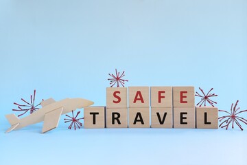 Wooden airplane model with blocks on sky blue background with coronavirus. Fly and travel safe...