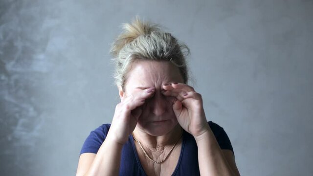 A portrait of an adult woman rubbing her eyes. Woman rubs her eyes from fatigue and weakness after feeling unwell