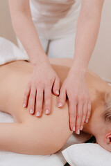 Fototapeta na wymiar Back massage. The masseuse massages the woman's back. Hand movements of the masseur.
