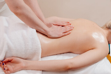 Obraz na płótnie Canvas Back massage. The masseuse massages the woman's back. Hand movements of the masseur.