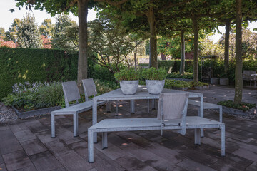 Modern iron garden furniture with a triangle table in a garden somewhere in the Netherlands