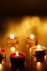 Burning candles with festive bokeh on a black background. Holiday concept. The concept of prayer and hope.