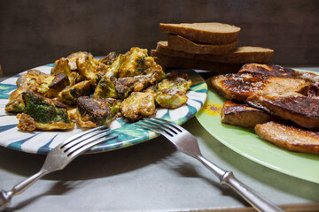 Baked cauliflower steaks with herbs and spices on baking sheet over black stone background.