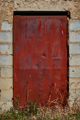 Rusty iron door closed in an old abandoned building full of vegetation