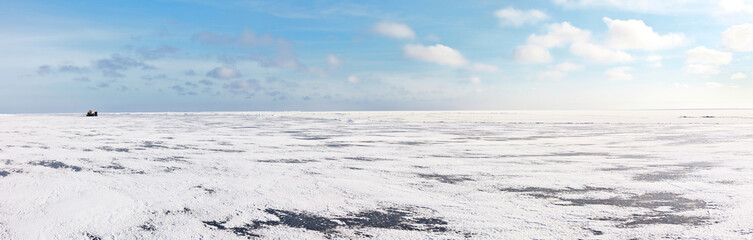 Obraz premium Endless white desert of snowy ice cover on frozen Lake Baikal on a frosty winter day. Tourists on the all-terrain vehicle Hivus travel across the icy expanses. Winter landscape. Natural background