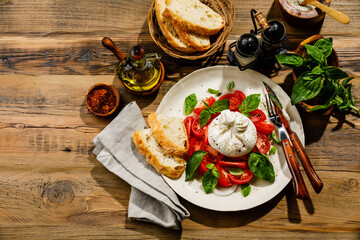 Salad with Tomatoes and Burrata cheese with basil and olive oil on wooden background