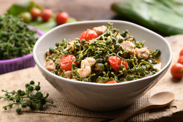 Northern Thai food (Kaeng Sa Lae), Spicy soup Broussonetia Kurzii with pork and tomatoes in a bowl on wooden background, Seasonal food in North Thailand