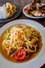green papaya salad in black plate on wooden background