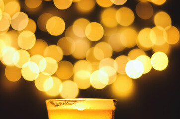 Burning candles with festive bokeh on a black background. Holiday concept. The concept of prayer and hope.