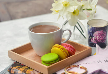 Top shot of a table with a cup of coffee and a bouquet of spring flowers on a white table top. coffee, magazines and cake. Top view flat style. Close up, copy space