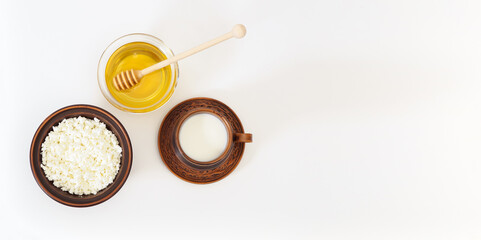 Banner with breakfast in handmade clay antique dishes with birch bark trim and fresh natural honey on white background with copy space, top view, flat layered design. Farmed organic dairy products in