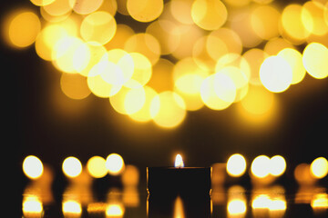 Burning candles with festive bokeh on a black background. Holiday concept. The concept of prayer and hope.