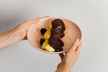 Cheesecakes with jam in a plate in the woman's hands. Pancakes with jam on a plate.
