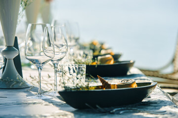 Festive table decor wine glasses and table setting in on the beach.. Preparing for an open-air party in the beach. Focus on dish with wineglass