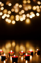 Burning candles with festive bokeh on a black background. Holiday concept. The concept of prayer and hope.